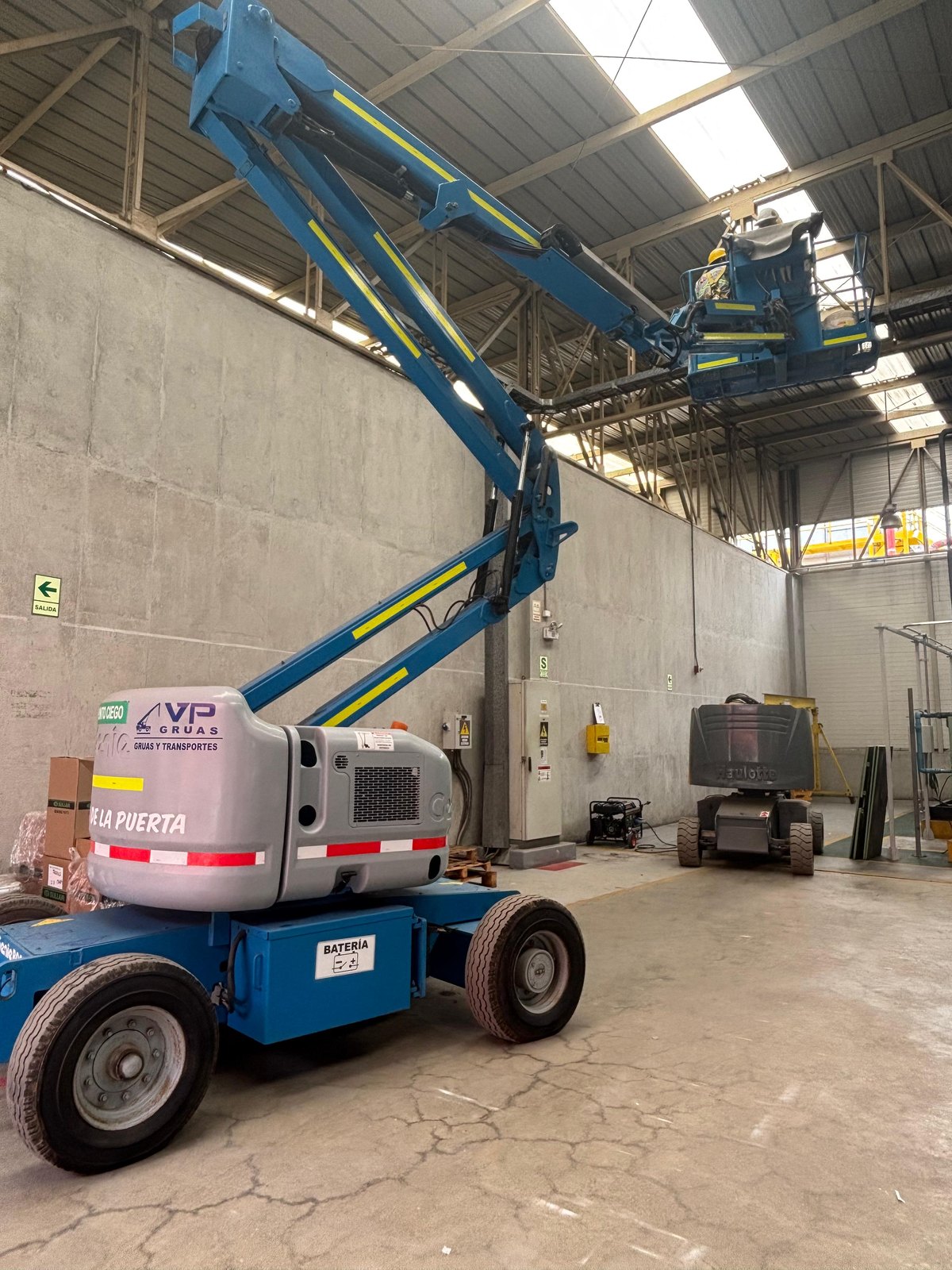 Plataforma articulada azul trabajando en una instalación industrial